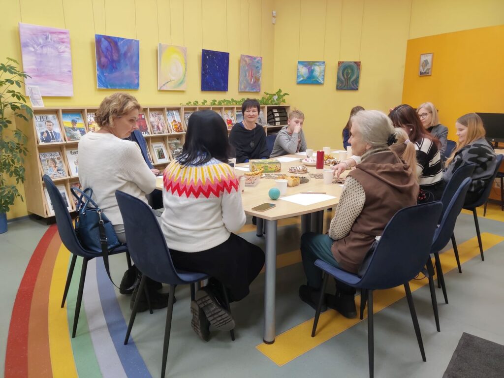 Moterys ir berniukas prie stalo bibliotekoje