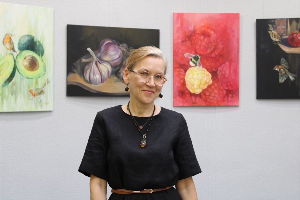 Diana Masiulienė savo tapybos darbų fone