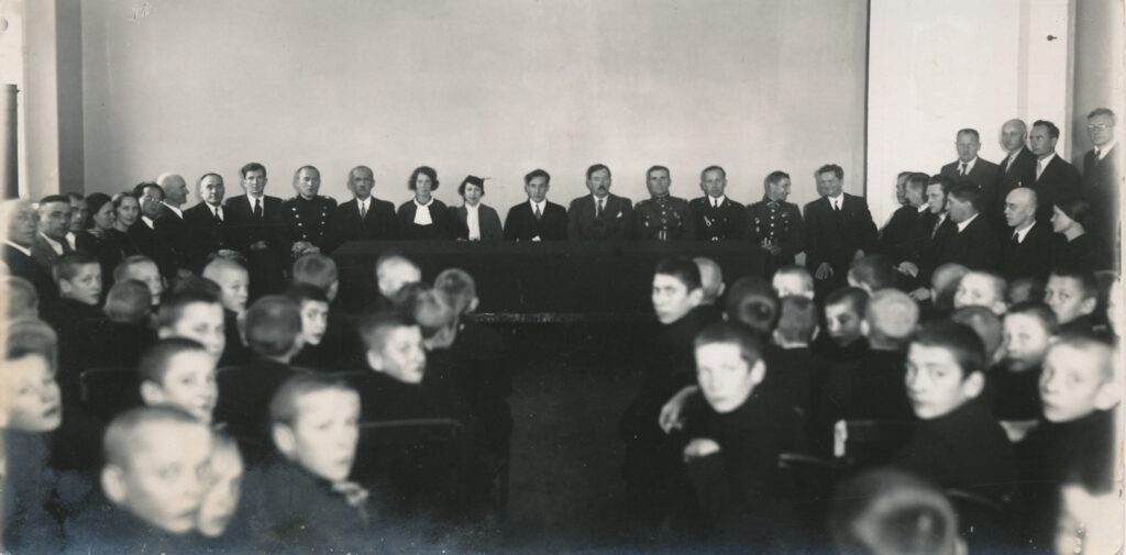 JAV lietuvių lakūnas Feliksas Vaitkus su žmona, Panevėžio miesto burmistras T. Chodakauskas ir kiti lydintieji asmenys su Panevėžio valstybinės gimnazijos bendruomene. Nuotrauka juodai balta.