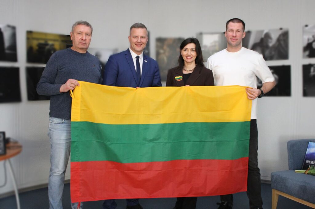 Trys vyrai ir moteris laiko prieš save išskleidę Lietuvos trispalvę