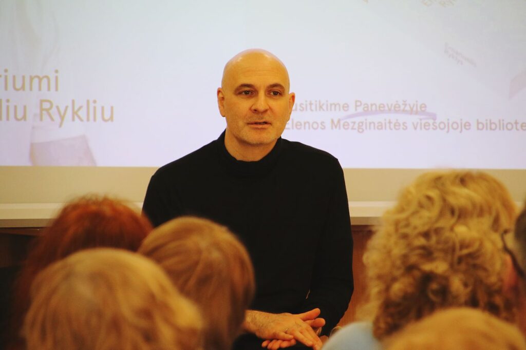 Vyras sėdi prieš auditoriją